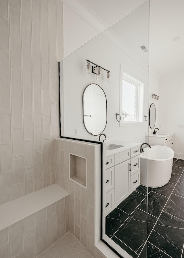 bathroom with visible vents, a soaking tub, ornamental molding, marble finish floor, and a sink