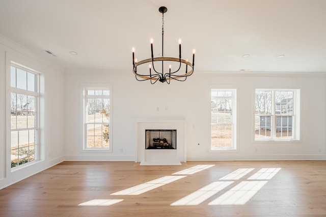 unfurnished living room featuring light wood finished floors, a fireplace with flush hearth, and a healthy amount of sunlight