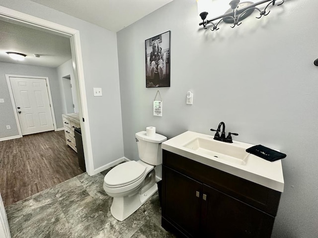 bathroom featuring vanity, toilet, and baseboards