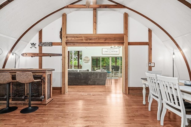 interior space with high vaulted ceiling, arched walkways, and wood finished floors