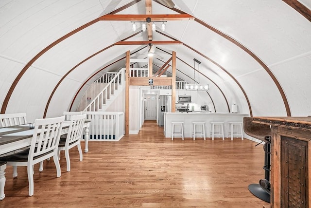 interior space with a notable chandelier, vaulted ceiling, and wood finished floors