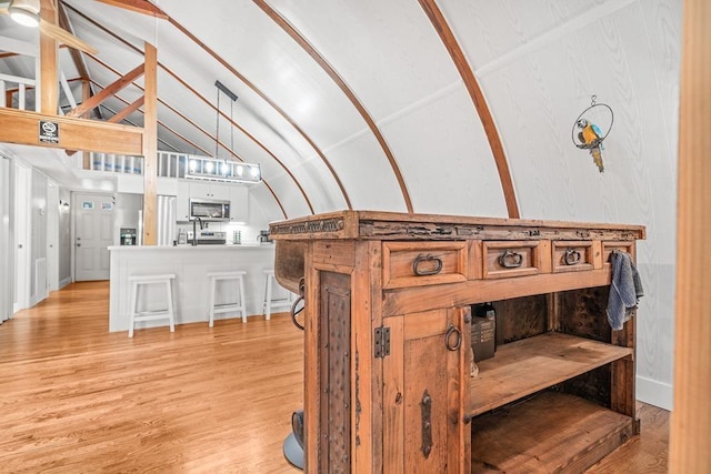 interior space with light wood-type flooring, lofted ceiling with beams, and baseboards