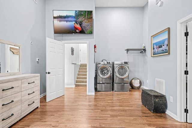 laundry room featuring visible vents, a high ceiling, washing machine and dryer, light wood-type flooring, and laundry area