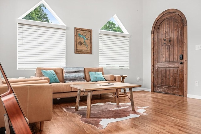 sitting room with arched walkways, light wood finished floors, and baseboards