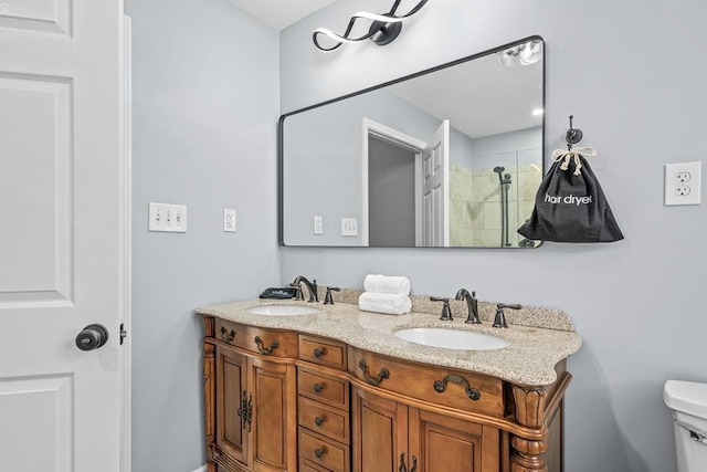 bathroom with tiled shower, a sink, toilet, and double vanity