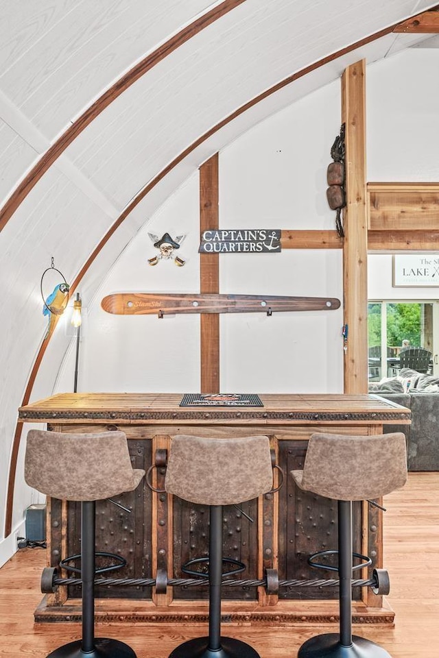 bar with vaulted ceiling and wood finished floors