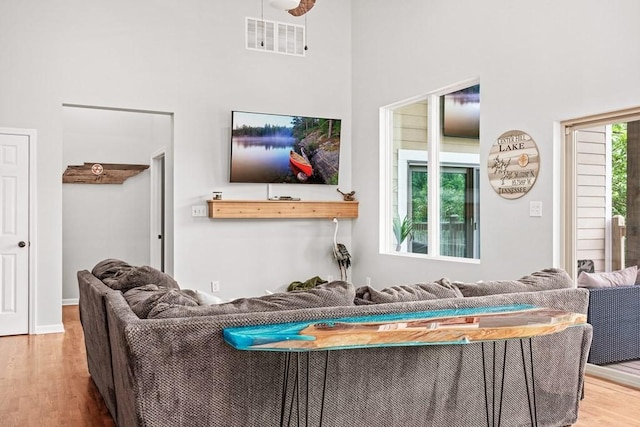 living area with visible vents, a towering ceiling, and wood finished floors