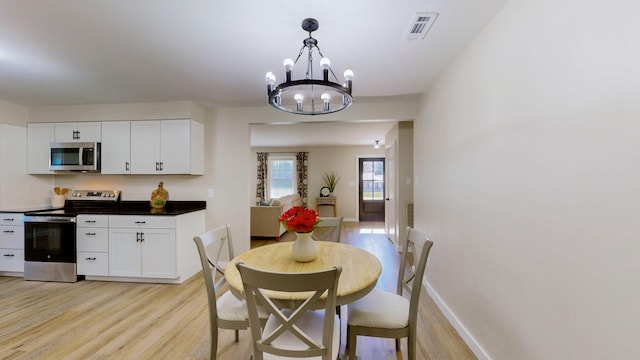 dining room with light wood-style flooring, visible vents, baseboards, and a notable chandelier