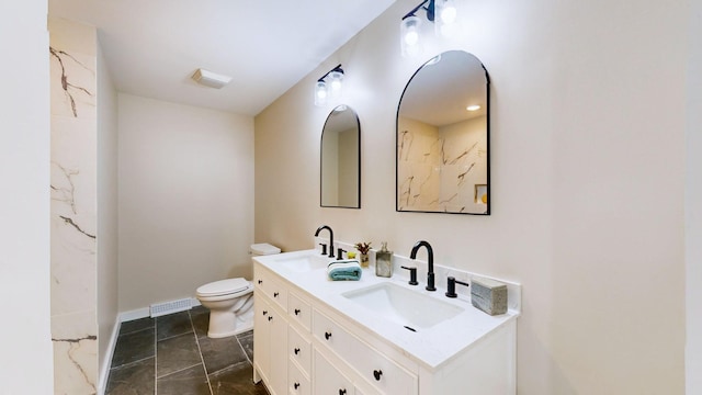 full bathroom with toilet, double vanity, visible vents, and a sink