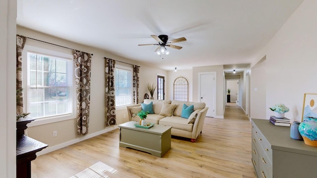 living room featuring light wood finished floors, baseboards, and a ceiling fan