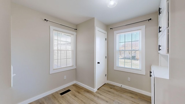 doorway to outside with light wood-type flooring, visible vents, and baseboards