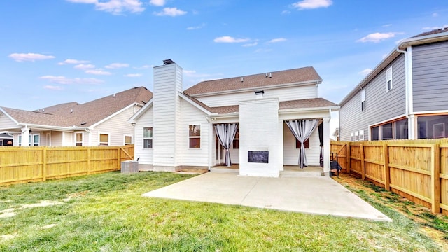 back of house with a shingled roof, a lawn, a patio, a fenced backyard, and a chimney