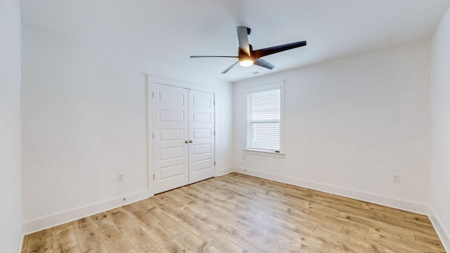 unfurnished bedroom with light wood-style floors, a ceiling fan, baseboards, and a closet