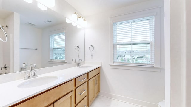 bathroom with double vanity, baseboards, visible vents, and a sink