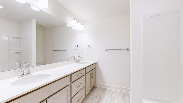 bathroom with double vanity, baseboards, visible vents, and a sink