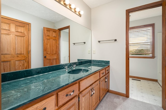 bathroom featuring visible vents, vanity, baseboards, and tile patterned floors