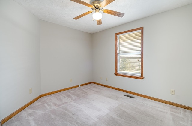 empty room featuring carpet floors, visible vents, a ceiling fan, a textured ceiling, and baseboards