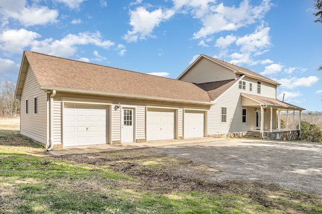 view of side of property featuring driveway, a shingled roof, and a porch