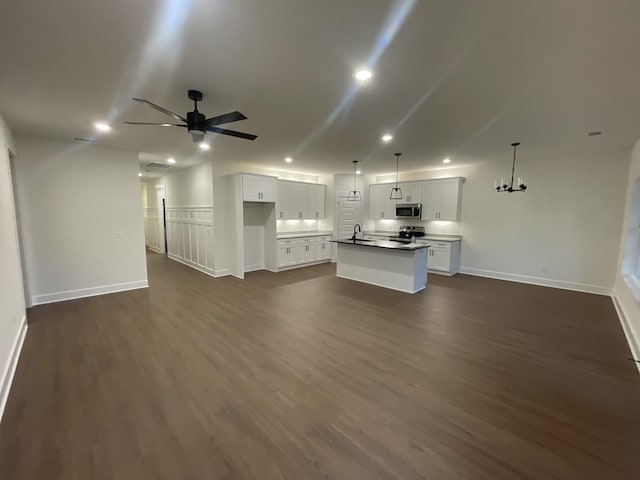 unfurnished living room featuring ceiling fan with notable chandelier, dark wood-type flooring, a sink, and recessed lighting