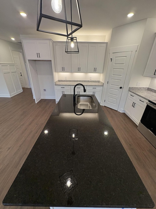 kitchen with dark wood-style flooring, white cabinets, a sink, and stainless steel electric range