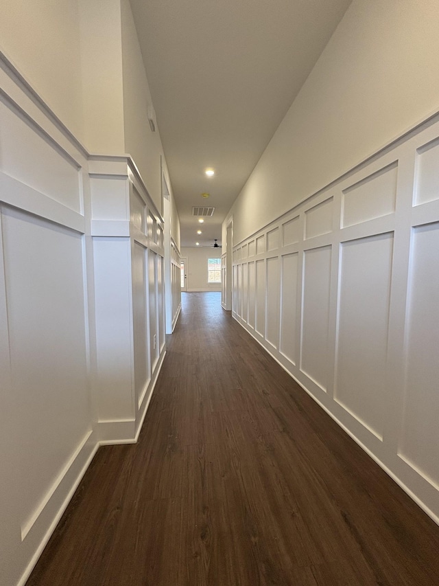 corridor featuring dark wood-style floors, visible vents, and a decorative wall