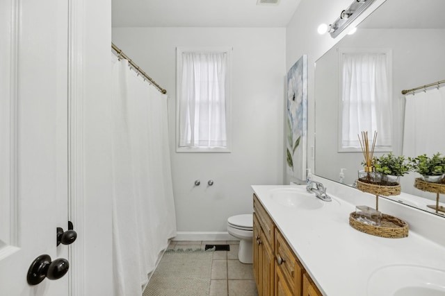 full bath featuring toilet, a sink, baseboards, tile patterned floors, and double vanity