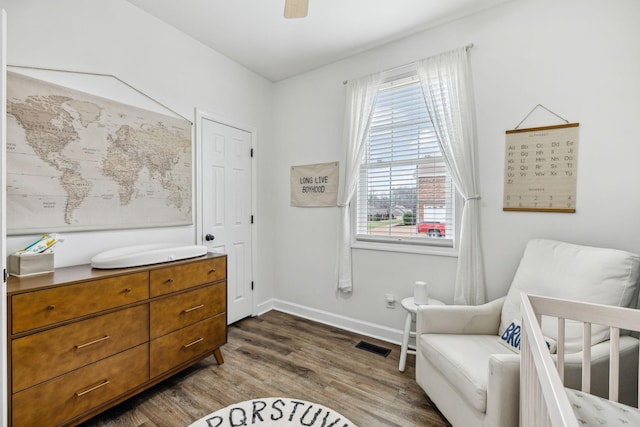 sitting room featuring ceiling fan, visible vents, baseboards, and dark wood finished floors