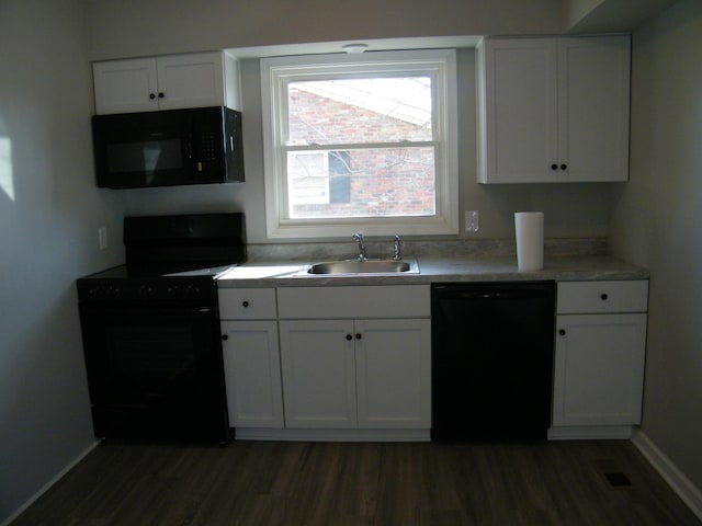 kitchen featuring dark wood-style flooring, a sink, visible vents, white cabinets, and black appliances