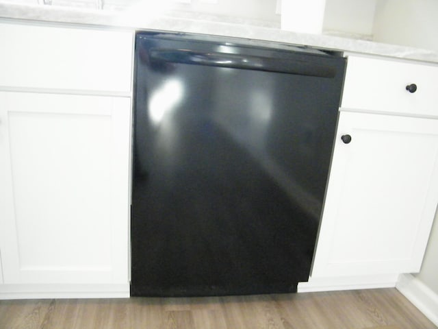 interior details with black dishwasher, light wood-style flooring, and white cabinetry