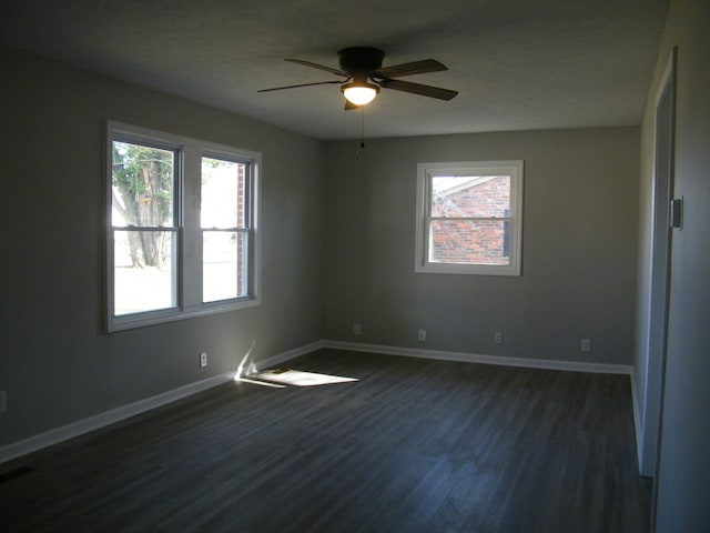 spare room featuring dark wood-style floors, visible vents, ceiling fan, and baseboards