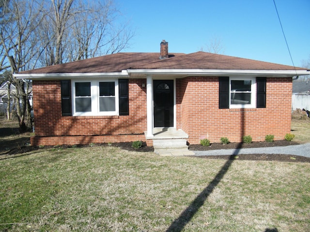 view of front of home with a chimney, a front lawn, and brick siding