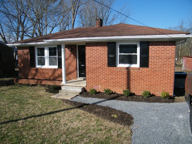 bungalow-style house featuring brick siding, a front lawn, and a chimney