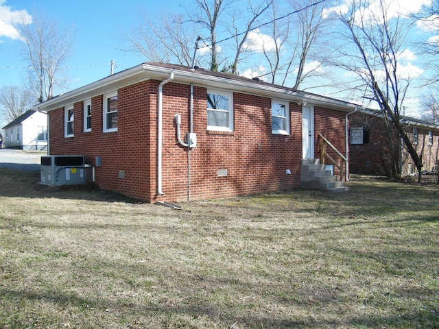 view of property exterior with entry steps, central AC unit, brick siding, a yard, and crawl space