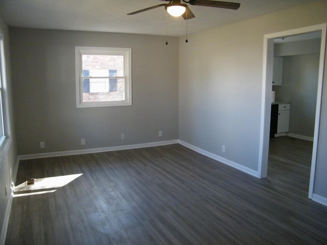 empty room with dark wood-type flooring, visible vents, ceiling fan, and baseboards