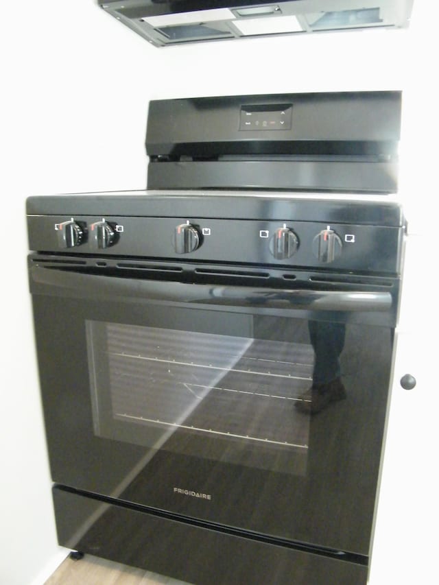 interior details with black range with gas stovetop and wood finished floors