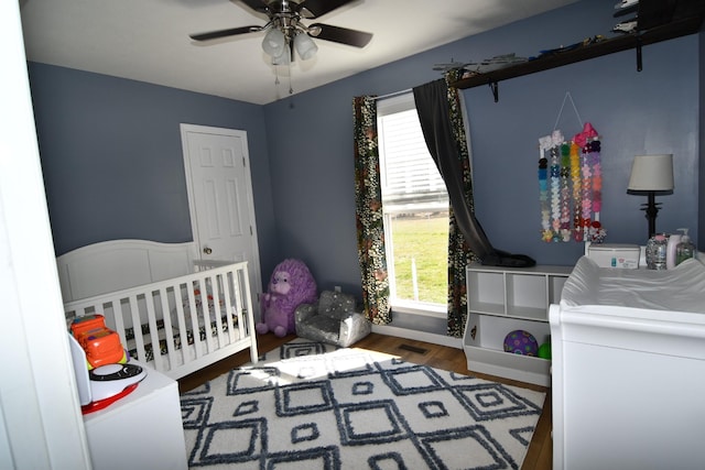 bedroom with a nursery area, multiple windows, wood finished floors, and visible vents