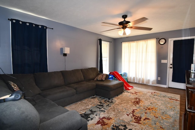 living area with a ceiling fan, baseboards, and wood finished floors