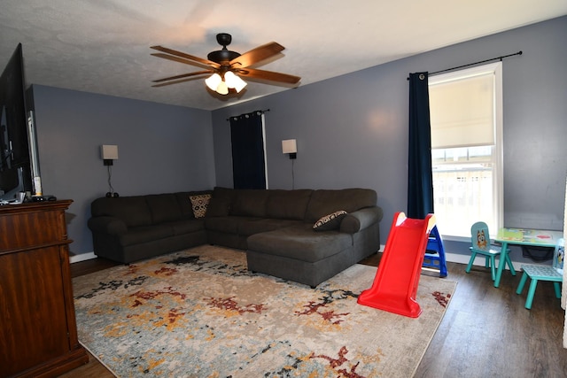 living room with a ceiling fan, a textured ceiling, baseboards, and wood finished floors