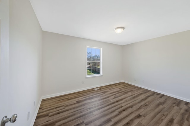 unfurnished room featuring wood finished floors, visible vents, and baseboards