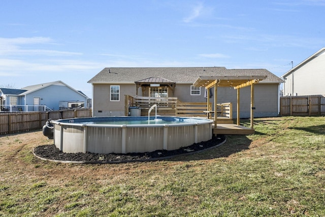 rear view of property with a fenced in pool, a fenced backyard, a yard, and a deck