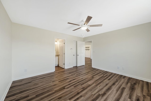 unfurnished bedroom featuring ensuite bath, ceiling fan, baseboards, and dark wood-style flooring