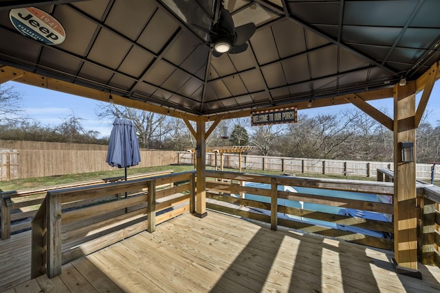 deck featuring a ceiling fan, a fenced backyard, and a gazebo