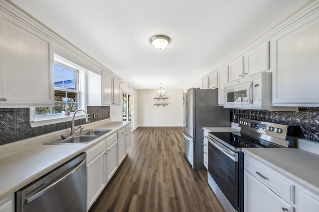 kitchen featuring appliances with stainless steel finishes, a sink, white cabinetry, and tasteful backsplash