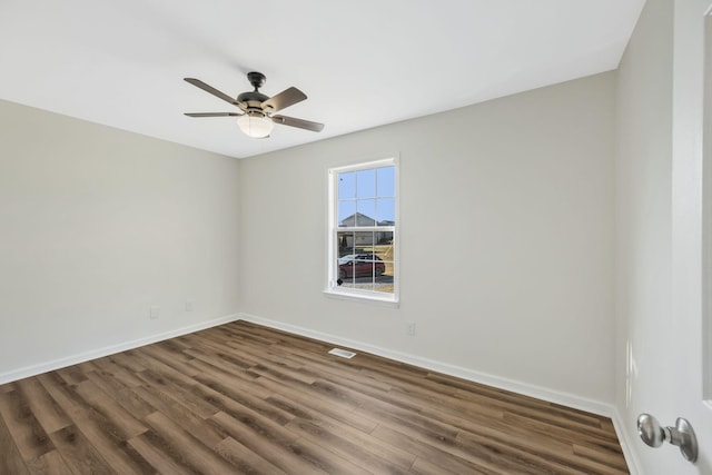 spare room with visible vents, dark wood finished floors, a ceiling fan, and baseboards