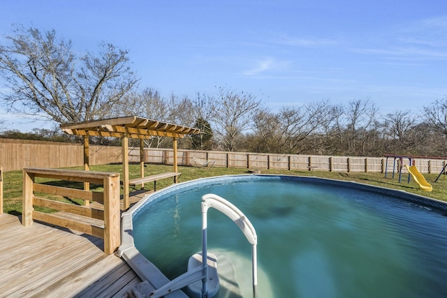 view of swimming pool featuring a fenced in pool, a playground, a lawn, a fenced backyard, and a wooden deck