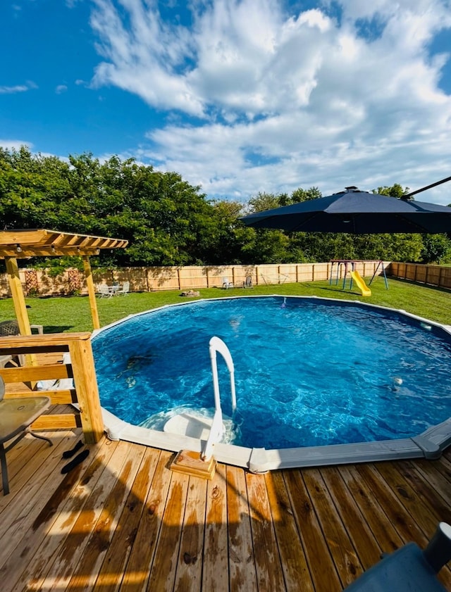 view of swimming pool with a fenced backyard, a yard, a deck, and a pergola