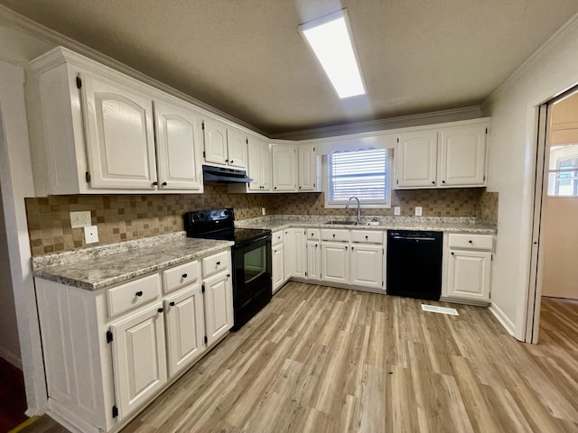 kitchen with light wood finished floors, white cabinets, a sink, under cabinet range hood, and black appliances