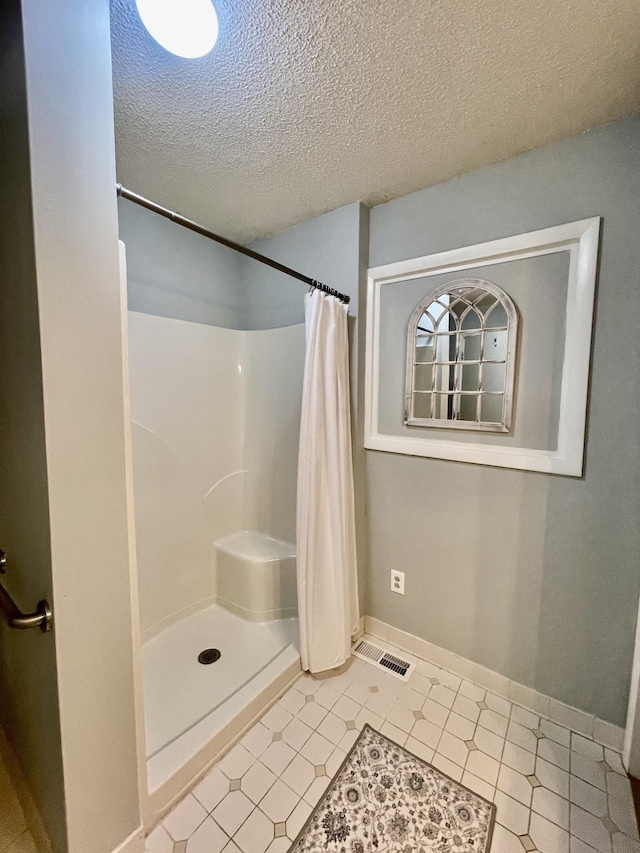 full bathroom with baseboards, visible vents, and a shower with shower curtain