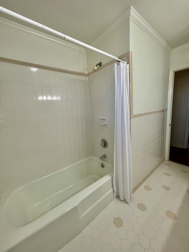 bathroom featuring a textured ceiling, tile patterned flooring, a wainscoted wall, tile walls, and crown molding