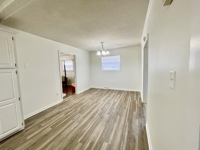 interior space with a textured ceiling, light wood-type flooring, baseboards, and an inviting chandelier